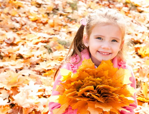 Осенний портрет милой улыбающейся маленькой девочки с кленовыми листьями — стоковое фото