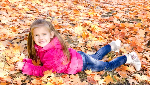 Retrato de outono de menina sorridente bonito deitado em licença de bordo — Fotografia de Stock