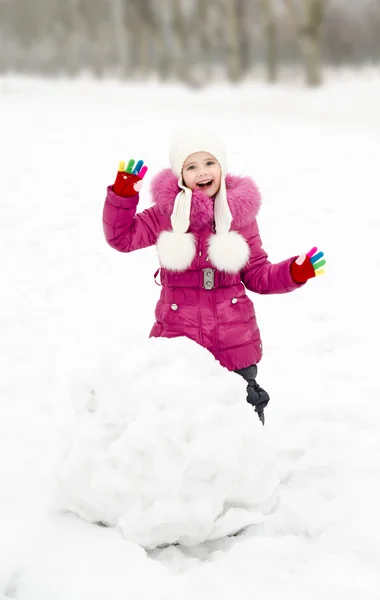 Cute smiling little girl makes snowman in winter day — Stock Photo, Image