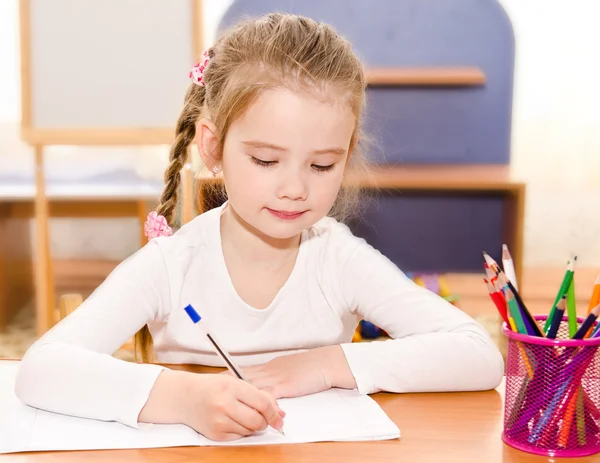 Carina bambina sta scrivendo alla scrivania — Foto Stock