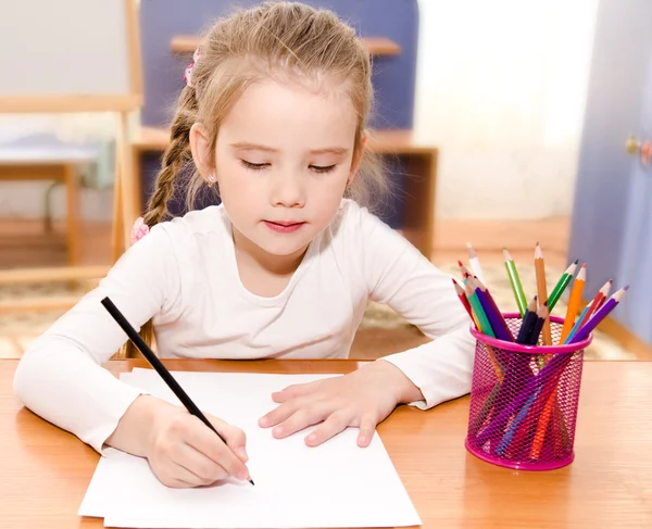 Χαριτωμένο κοριτσάκι γράφει στο γραφείο — Φωτογραφία Αρχείου