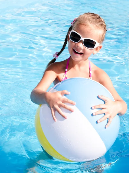 Улыбающаяся маленькая девочка с мячом в бассейне — стоковое фото