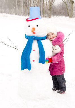 Portrait of smiling little girl with snowman