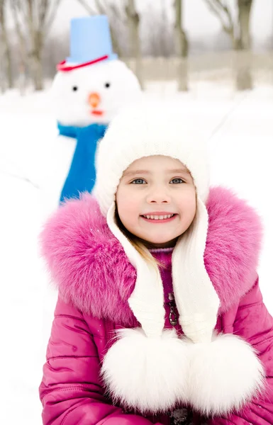 Portrait of smiling little girl with snowman — Stok fotoğraf