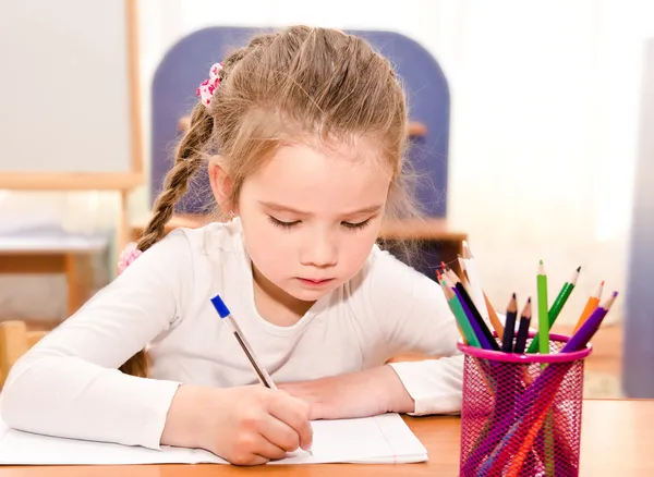 Nettes kleines Mädchen schreibt am Schreibtisch — Stockfoto