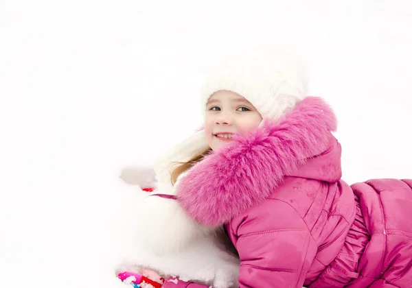 Söt leende liten flicka liggande på snö i vinterdag — Stockfoto