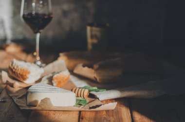 Brie peyniri, kırmızı şarap, bal ve ekmek ile ahşap bir masada akşam yemeği.