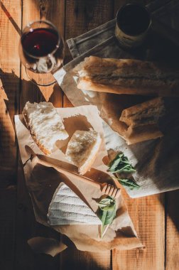 Brie peyniri, kırmızı şarap, bal ve ekmek ile ahşap bir masada akşam yemeği.