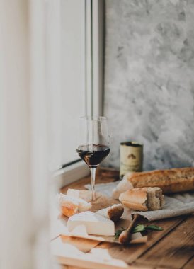 Brie peyniri, kırmızı şarap, bal ve ekmek ile ahşap bir masada akşam yemeği.