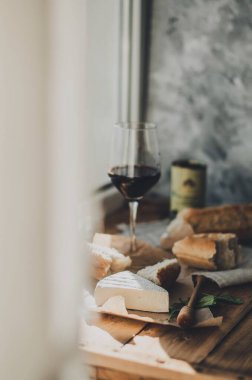 Brie peyniri, kırmızı şarap, bal ve ekmek ile ahşap bir masada akşam yemeği.