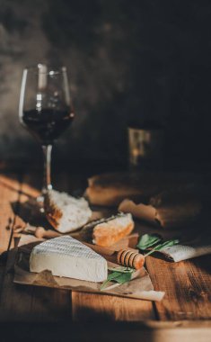 Brie peyniri, kırmızı şarap, bal ve ekmek ile ahşap bir masada akşam yemeği.