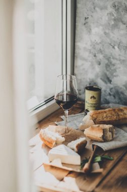 Brie peyniri, kırmızı şarap, bal ve ekmek ile ahşap bir masada akşam yemeği.