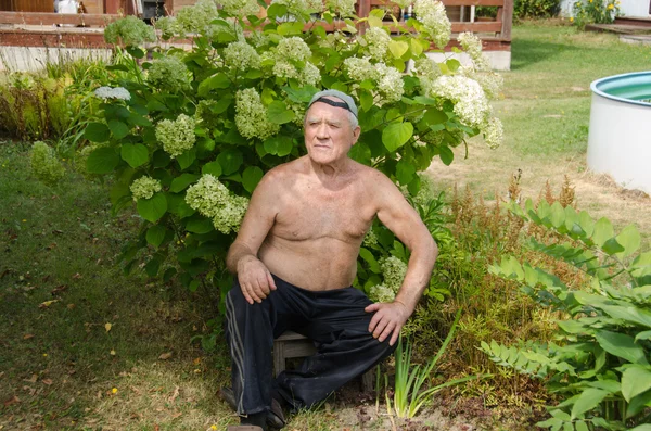 The elderly man has a rest in a garden — Stock Photo, Image