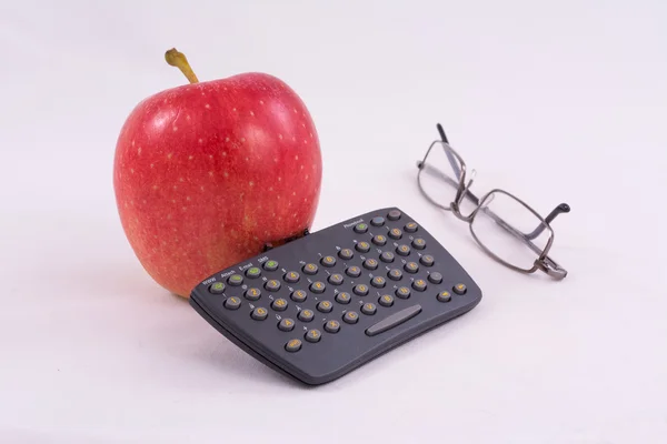 Красное яблоко с мини-клавиатурой и очками на белом фоне — стоковое фото