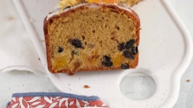 Üst Manzara. Masada roma batırılmış dilimlenmiş meyveli kek var. Arka planda fenerler olan bir Noel atmosferi. Ev yapımı Noel çöreği. Kurutulmuş meyveli geleneksel kek. Kamera hareketi.