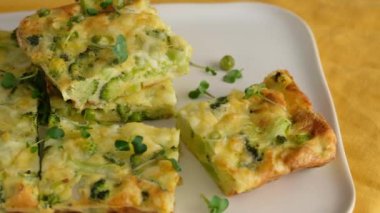 Yakın çekim kamera hareketi. Tabakta brokoli olan frittata. İtalyan kahvaltısı. Fırında omlet, sebze ve brokoli ile servis tabağında. Sağlıklı kahvaltı. Üst görünüm.