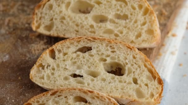 Kamerabewegung. Ansicht von oben. Brot in Scheiben liegt auf einem Holzbrett. Brot backen. Die Ciabatta kochen. Italienisches Brot. — Stockvideo