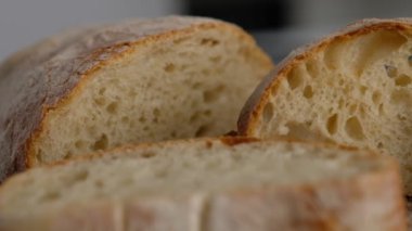 Kamera hareketi. Üst Manzara. Dilimlenmiş ekmek tahta bir tahtanın üzerinde yatıyor. Ekmek pişiriyorum. Ciabatta pişiriyorum. İtalyan ekmeği.