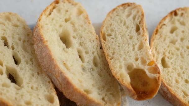 Movimento da câmara. Vista superior. O pão fatiado está em uma tábua de madeira. Pão para assar. Cozinhar a ciabatta. Pão italiano. — Vídeo de Stock