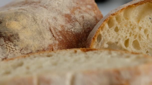 Kameramozgás. Első látásra. A szeletelt kenyér egy fából készült deszkán fekszik. Kenyeret sütök. Megfőzöm a ciabattát. Olasz kenyér. — Stock videók