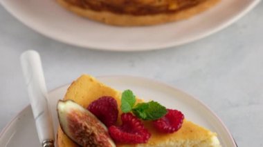 Yakın plan. Kadın eli böğürtlenli cheesecake kesti ve tabağa koydu. Çilek, ahududu ve incirle süslenmiş lezzetli ev yapımı kremalı turta. Tatlı sunumu. en üstteki görünüm