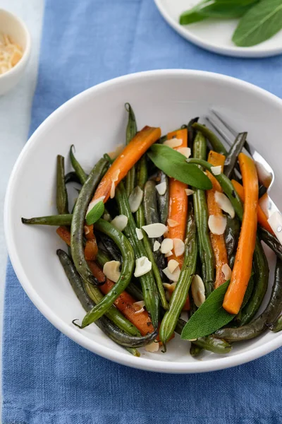 用橄榄油和鼠尾草烹调的绿豆和胡萝卜。健康食品. 图库图片