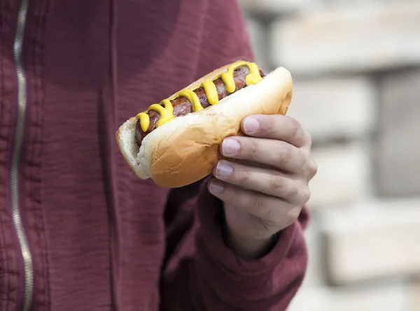 Homme mangeant un hot dog à la moutarde — Photo