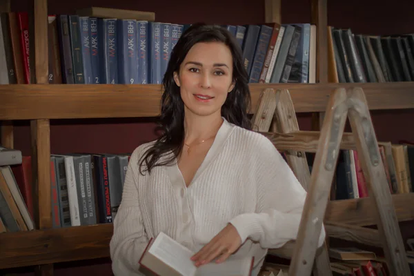 Kütüphanede bir kadın kitap okuyor.