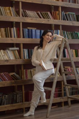 Kütüphanede bir kadın kitap okuyor.