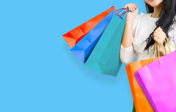 青の背景にショッピングバッグを持つ幸せな若いアジアの女性 — ストック写真
