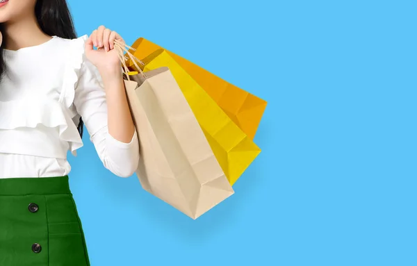 青の背景にショッピングバッグを持つ幸せな若いアジアの女性 — ストック写真
