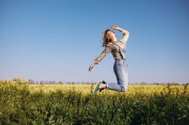 Çiçek tarlasında zıplayan mutlu kız