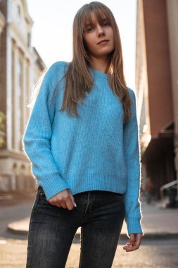 Şehir sokaklarında poz veren genç bir kadının portresi. Sarışın model dışarıda duruyor ve kameraya bakıyor.