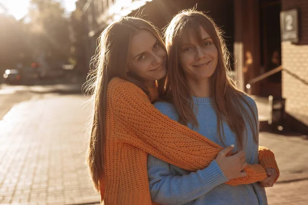 쌍둥이 자매는 카메라 앞에서 석양을 배경으로 도시의 거리에서 포즈를 취하고 — 스톡 사진
