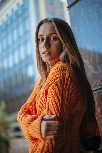 blonde woman looking over the shoulder at the camera. Warm knitted pullover. 