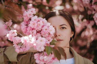 Yüzü, çiçek açan sakura dallarında genç ve güzel Asyalı bir kadının portresiyle kaplıydı.
