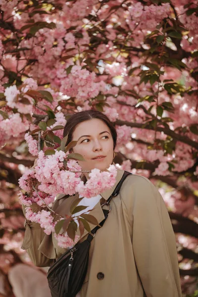 Japon Sacura ağacının çiçek açan dallarıyla poz veren romantik bir kadın model.
