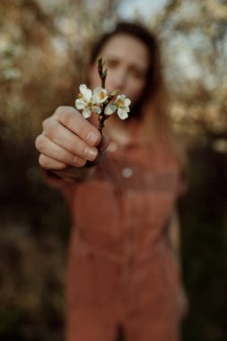 Kolunda çiçek açan kadın modelin bulanık portresi. Kameraya çiçek veren kadın 