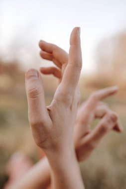 Bulanık arka planda kadın elleri gökyüzüne uzanıyor.