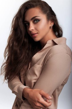 Romantik, güzel, melez kadın kameraya bakıyor. Kadın model kendine sarılıyor. İç mekan