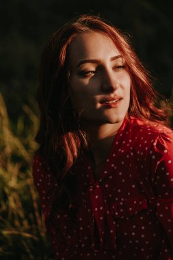 Parkta poz veren, güzel kırmızı elbiseli çekici, esmer bir kadının fotoğrafını çek.