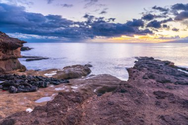Tenerife kanarya adasında kayalar ve mavi sularla güzel bir gün batımı