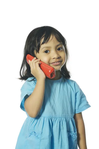 Маленькая девочка держит красный беспроводной телефон — стоковое фото