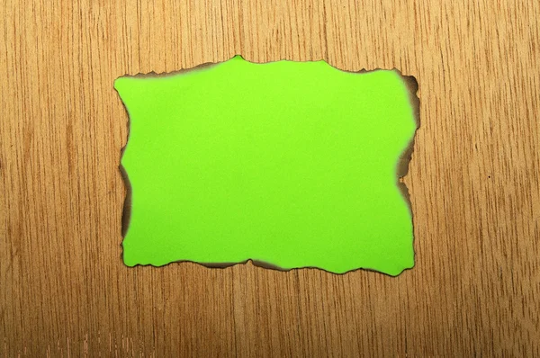 Papel queimado verde sobre fundo de madeira — Fotografia de Stock