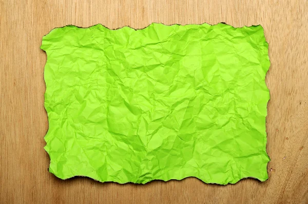 Papel queimado verde sobre fundo de madeira — Fotografia de Stock