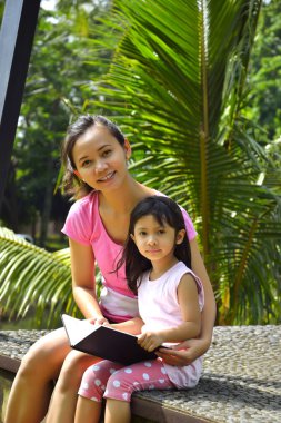 Anne ve kızı kitap okuyor.