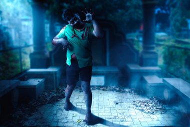 Mezarlıkta yürürken vücudunda kan ve yara olan korkunç bir zombi.