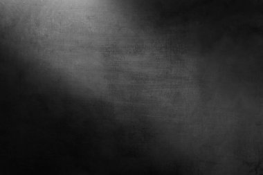 Karanlık odada ışığı olan beton bir duvar.