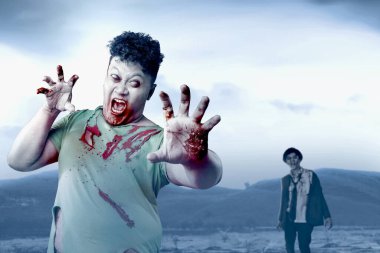 Vücudunda kan ve yara olan korkunç bir zombi sahada yürüyor.