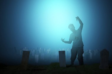 Mezarlıkta yürürken vücudunda kan ve yara olan korkunç bir zombi.